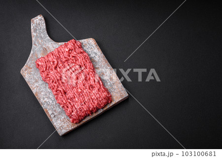 Raw ground beef or pork on a wooden cutting board with spices and salt 103100681