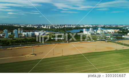 Border of two fields. Blooming yellow rapeseed and cereal sprouts. A city is visible on the horizon. Aerial photography. Border of two fields. Blooming yellow rapeseed and cereal sprouts. A city is visible on the horizon. Aerial photography. 103101687