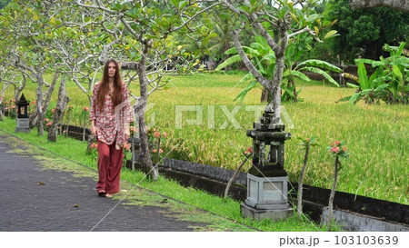 beautiful young woman walks through a tropical park, a religious place in indonesia beautiful young woman walks through a tropical park, a religious place in indonesia 103103639