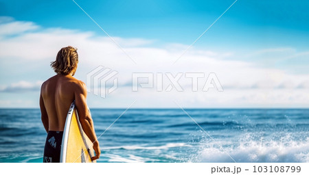 Happy guy in beachwear holding a surfboard. Surfer back view, looking at the ocean with summer sky. People in water sport adventure camp, extreme activity on family summer beach vacation. Watersport 103108799