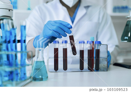 Chemist scientist holding test tube and tablet conducting experiment in laboratory with equipment, science concept. Chemist scientist holding test tube and tablet conducting experiment in laboratory with equipment, science concept. 103109523
