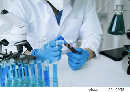 Chemist scientist holding test tube and tablet conducting experiment in laboratory with equipment, science concept. Chemist scientist holding test tube and tablet conducting experiment in laboratory with equipment, science concept. 103109524