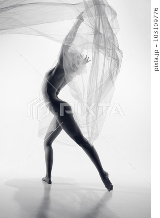 Portrait of young beautiful woman holding piece of transparent cloth in front her body. Naked female model posing over monochrome studio background 103109776