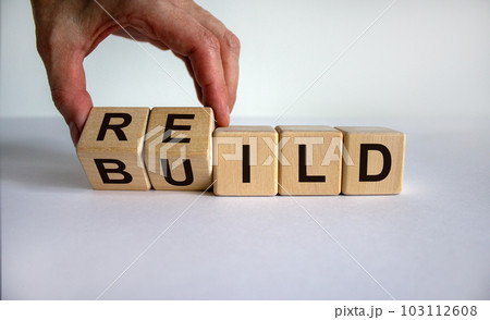 Concept word 'rebuild' on cubes on a beautiful wooden table. Male hand. White background. Business concept. Copy space. Concept word 'rebuild' on cubes on a beautiful wooden table. Male hand. White background. Business concept. Copy space. 103112608