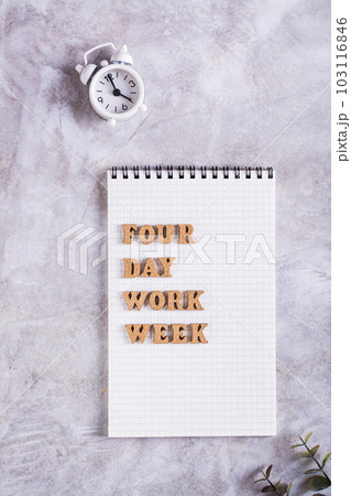 Four day work week concept wooden letters on notebook and alarm clock top and vertical view Four day work week concept wooden letters on notebook and alarm clock top and vertical view 103116846