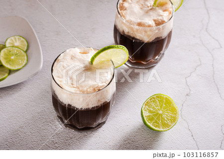 Alcohol free dirty soda cocktail of cola, whipped cream and lime in glasses Alcohol free dirty soda cocktail of cola, whipped cream and lime in glasses 103116857