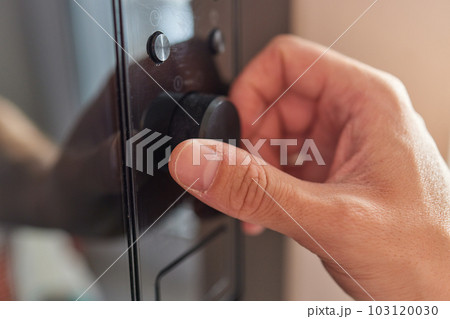 Hand pushing button of microwave oven for cooking food in kitchen 103120030