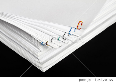 Stacks of papers with multicolored paper clips on a dark background 103120135