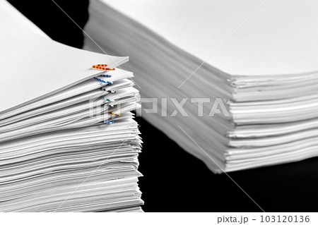 Stacks of papers with multicolored paper clips on a dark background 103120136