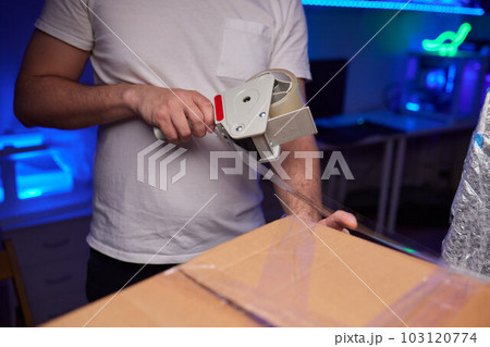 young man packing a monitor in a cardboard box. young man packing a monitor in a cardboard box. 103120774