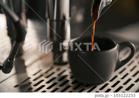 pulling espresso shot with single spout portafilter from coffee machine closeup pulling espresso shot with single spout portafilter from coffee machine closeup 103122233