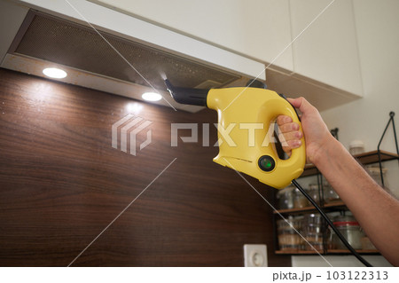 house cleaning. Girl brushes steam cleaners kitchen drawing with steam in green gloves. cleaning of a surface. light kitchen. house cleaning. Girl brushes steam cleaners kitchen drawing with steam in green gloves. cleaning of a surface. light kitchen. 103122313