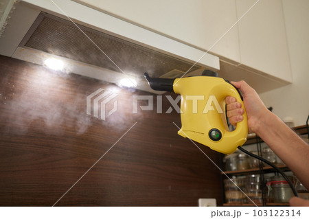 house cleaning. Girl brushes steam cleaners kitchen drawing with steam in green gloves. cleaning of a surface. light kitchen. house cleaning. Girl brushes steam cleaners kitchen drawing with steam in green gloves. cleaning of a surface. light kitchen. 103122314