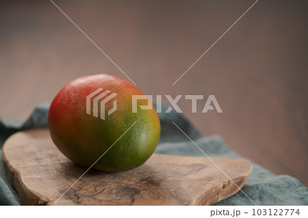 Whole ripe red mango on olive wood board 103122774