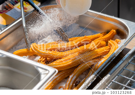 Chef preparing homemade crunchy churros at street food market: close up 103123268
