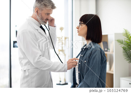 GP checking lungs of female with stethoscope in exam room GP checking lungs of female with stethoscope in exam room 103124769