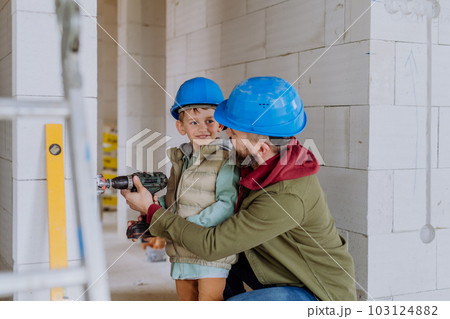Father and his little son working on their unfinished house. Father and his little son working on their unfinished house. 103124882