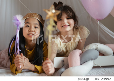 Happy girls playing princess with princess wands in a play tent. 103124992