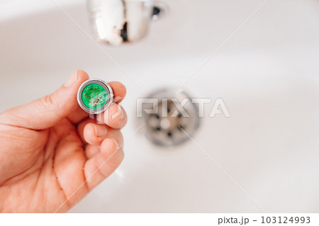 A plumber cleans a water purification filter in faucet faucets in a washbasin 103124993