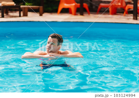 Portrait of a cheerful middle-aged man in the pool with inflatable lifebuoy. 103124994