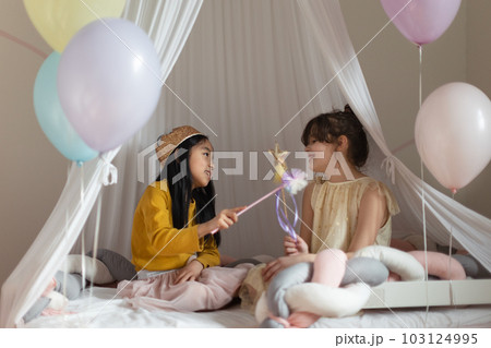 Happy girls playing princess with princess wands in a play tent. 103124995