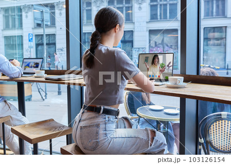 Virtual video chat of teenage girls friends, using laptop in cafe Virtual video chat of teenage girls friends, using laptop in cafe 103126154