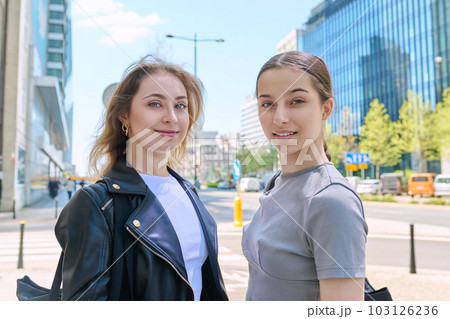 Two smiling female students looking at camera, urban modern background 103126236