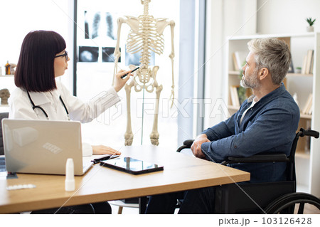 Therapist using skeleton to show injured site to patient Therapist using skeleton to show injured site to patient 103126428
