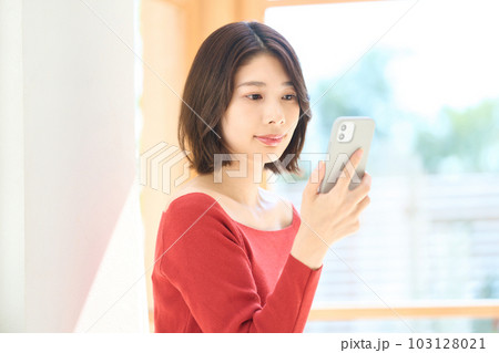 私服の若い女性 リビング スマホ 私服の若い女性 リビング スマホ 103128021