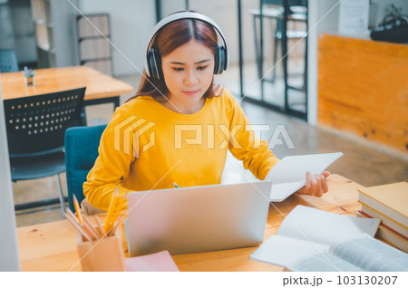 young student wearing headphones studies online, distance learning, and keeps up to date on the global coronavirus pandemic. 103130207