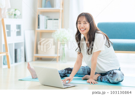 リビングでパソコンを見ながらオンラインヨガをする若い女性 リビングでパソコンを見ながらオンラインヨガをする若い女性 103130864