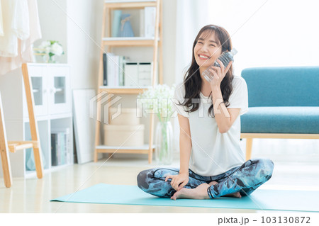 ヨガをしている時にミネラルウォーターを飲んで休憩をする若い女性 ヨガをしている時にミネラルウォーターを飲んで休憩をする若い女性 103130872