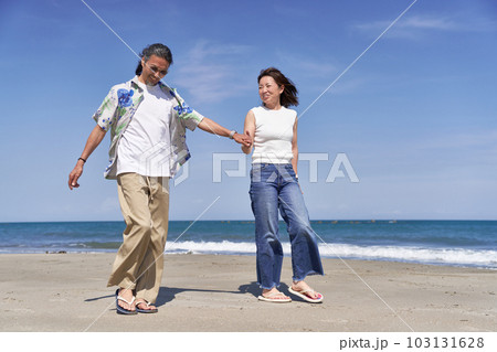 手をつないで海辺を歩くミドルシニアのカップル 103131628