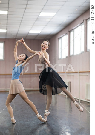 Two Asian ballerinas are dancing in the class.  103132862