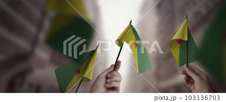 A group of people holding small flags of the French Guiana in their hands 103136703