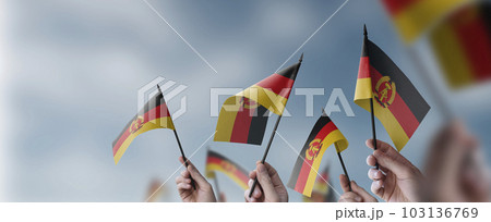 A group of people holding small flags of the DDR in their hands 103136769