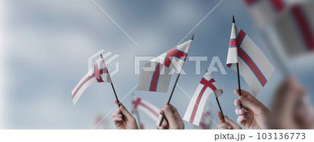 A group of people holding small flags of the Faroe Islands in their hands A group of people holding small flags of the Faroe Islands in their hands 103136773
