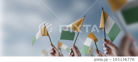 A group of people holding small flags of the Cote dIvoire in their hands 103136776
