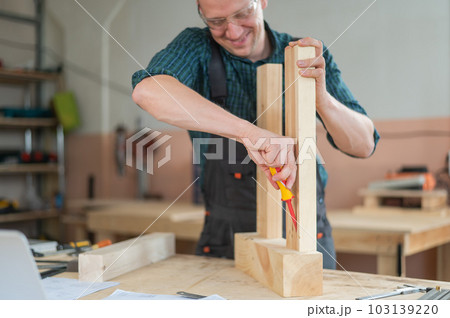 Caucasian man assembling a table with a screwdriver.  103139220