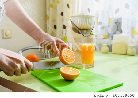 Woman is preparing fresh orange juice in the kitchen. Woman is preparing fresh orange juice in the kitchen. 103139650
