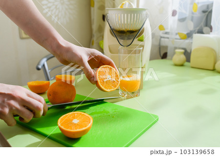 Woman is preparing fresh orange juice in the kitchen. 103139658