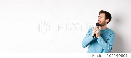Worried and confused man reading lyrics on karaoke, looking left with unsure face, holding microphone and singing, white background Worried and confused man reading lyrics on karaoke, looking left with unsure face, holding microphone and singing, white background 103140801