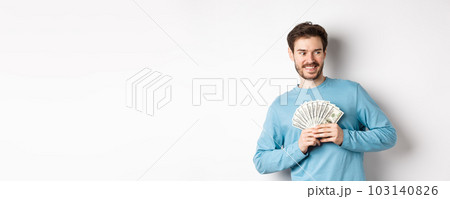 Greedy smiling man showing money and looking right, thinking about shopping, standing over white background Greedy smiling man showing money and looking right, thinking about shopping, standing over white background 103140826