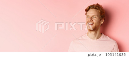 Close up of handsome young man with beard and red hair, looking left and smiling delighted, standing confident over pink background Close up of handsome young man with beard and red hair, looking left and smiling delighted, standing confident over pink background 103141026