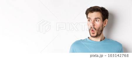 Close-up of impressed caucasian man saying wow, looking left amazed, checking out promotion deal, white background 103142768