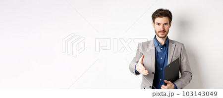 Confident businessman with clipboard giving hand for handshake, greeting business partners on meeting, standing on white background in suit 103143049