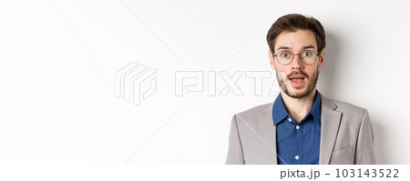 Close-up of surprised business man in glasses and suit gasping amazed, hear good news, standing on white background 103143522