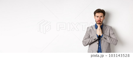 Miserable whining businessman asking for loan, need help and begging you, sobbing and say please with sad face, standing on white background, ask for forgiveness 103143528