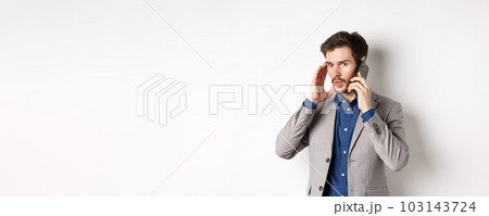 Businessman talking on phone and covering ear, receive call in loud place, cant hear caller, standing on white background 103143724