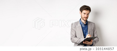Successful businessman in grey suit taking notes, working in office clothing, holding clipboard and looking at camera, white background 103144857
